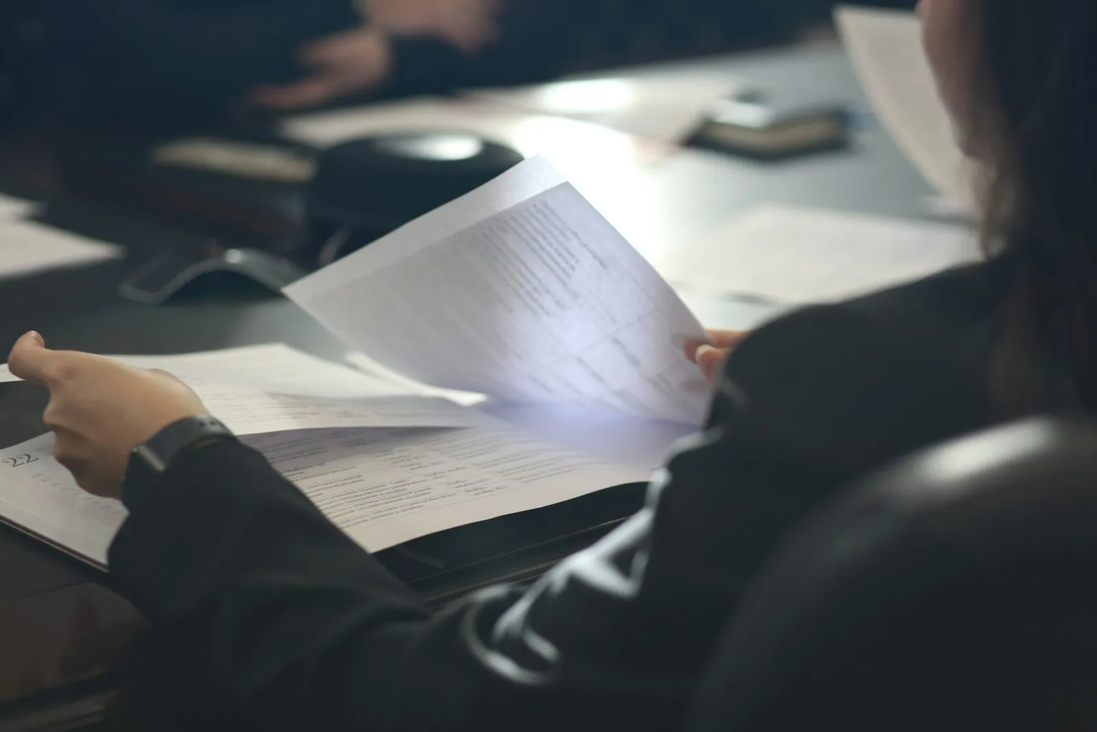 A woman reading a document at a meeting table.