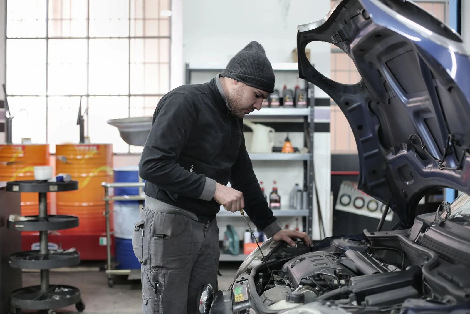 A mechanic leaning into a car's engine bay in a workshop.